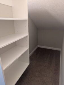 A tidy and empty closet with white shelves and carpet, reflecting the thorough house cleaning by Columbia Cleaners in Columbia, MO.