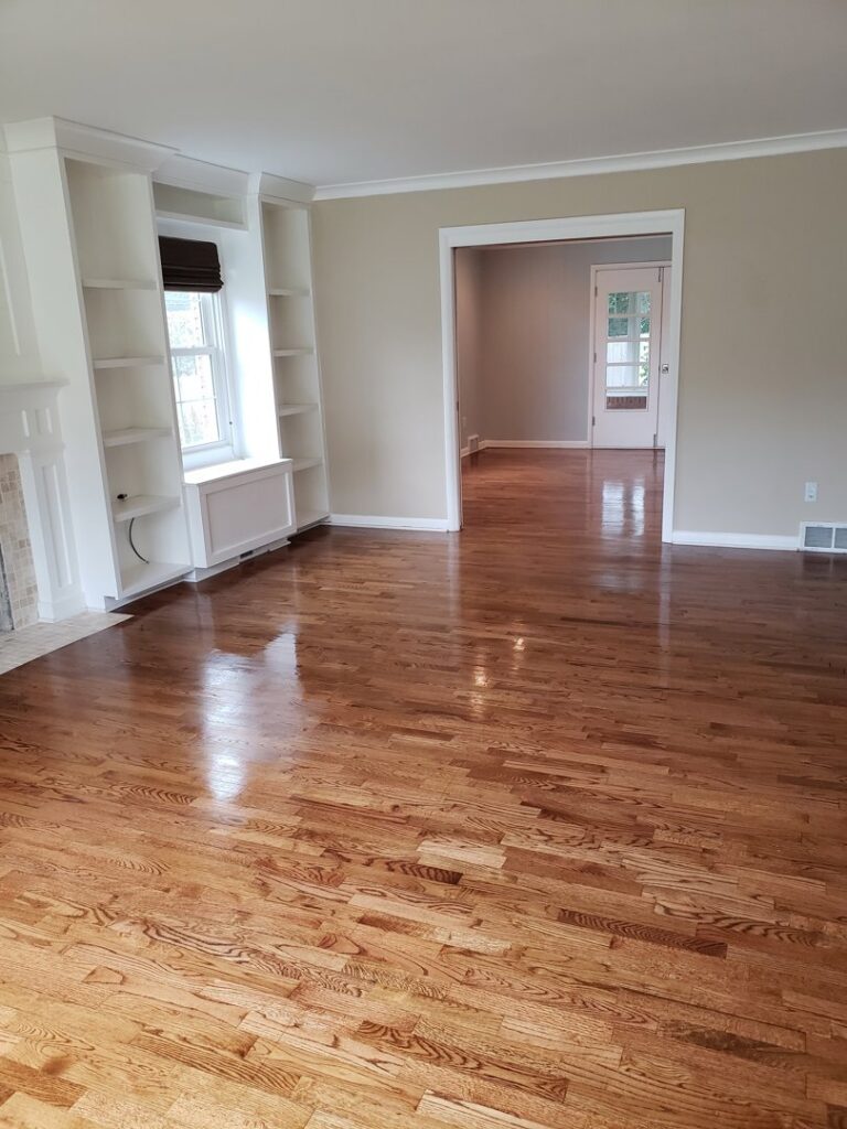 A tidy living room with polished hardwood floors and built-in shelves, professionally cleaned by A To Zen in Lansing, MI.