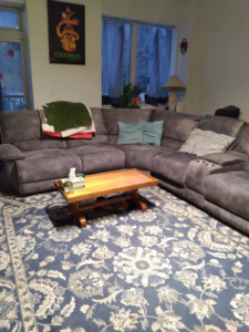 A beautifully tidy living room with a large sectional sofa, cleaned by Squeaky Clean By: Nikki in Chicago, IL.