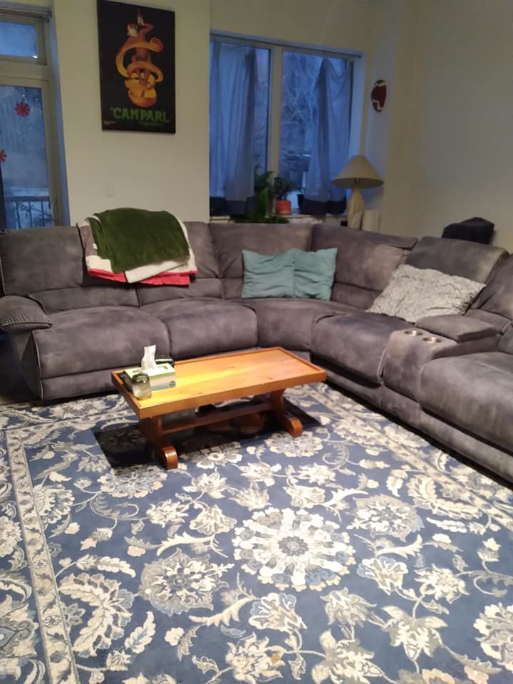 A beautifully tidy living room with a large sectional sofa, cleaned by Squeaky Clean By: Nikki in Chicago, IL.