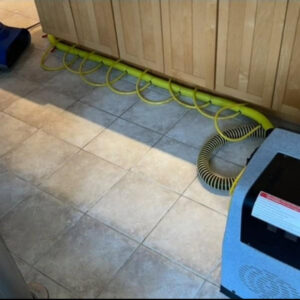 Specialized drying mats and hoses on a tiled floor for water damage restoration by New Method Restoration in Edison, NJ.