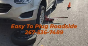A roadside assistance technician changing a flat tire for a car at Easy To Plug Roadside in Philadelphia, PA