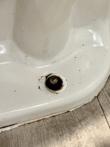 A close-up of a toilet base showing rust and water stains around the bolt, indicating a leak or water damage that Ciocca Cleaning & Restoration in Fort Wayne, IN can repair.