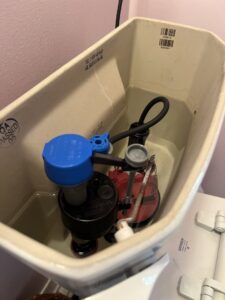 An open toilet tank showing water and internal mechanisms, indicating a potential leak or water issue, by BMR Contracting in Utica, NY