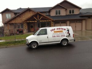 A Top Notch Cleaning LLC branded van parked in front of a residential house in Medford, OR, ready for a house cleaning job.