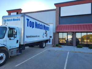 A Top Notch Movers truck backed up to a commercial building's loading dock in Madison, WI.