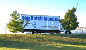 A Top Notch Movers truck parked on a grassy area with trees in Madison, WI, ready for service.