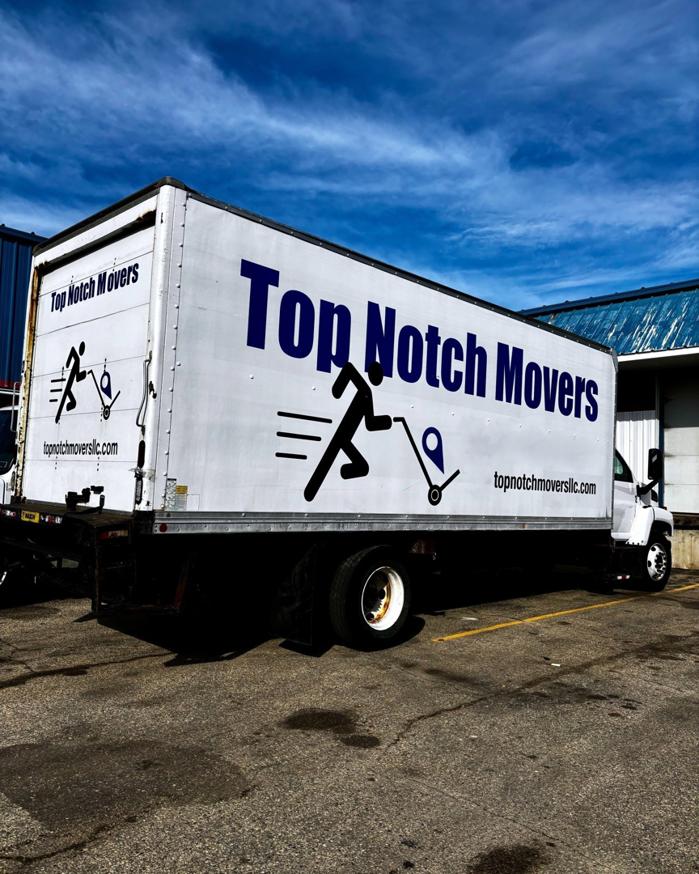 A Top Notch Movers truck parked in a lot under a bright blue sky in Madison, WI.