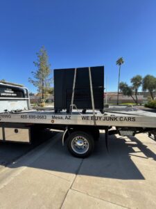 A C&B Towing flatbed truck hauling a large black toolbox or cabinet on a sunny day in Mesa, AZ.