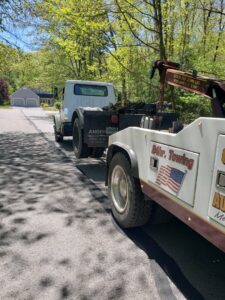 A tow truck from Bailey's Towing and Auto Body, LLC performing hook towing on another truck in Merrimack, NH.