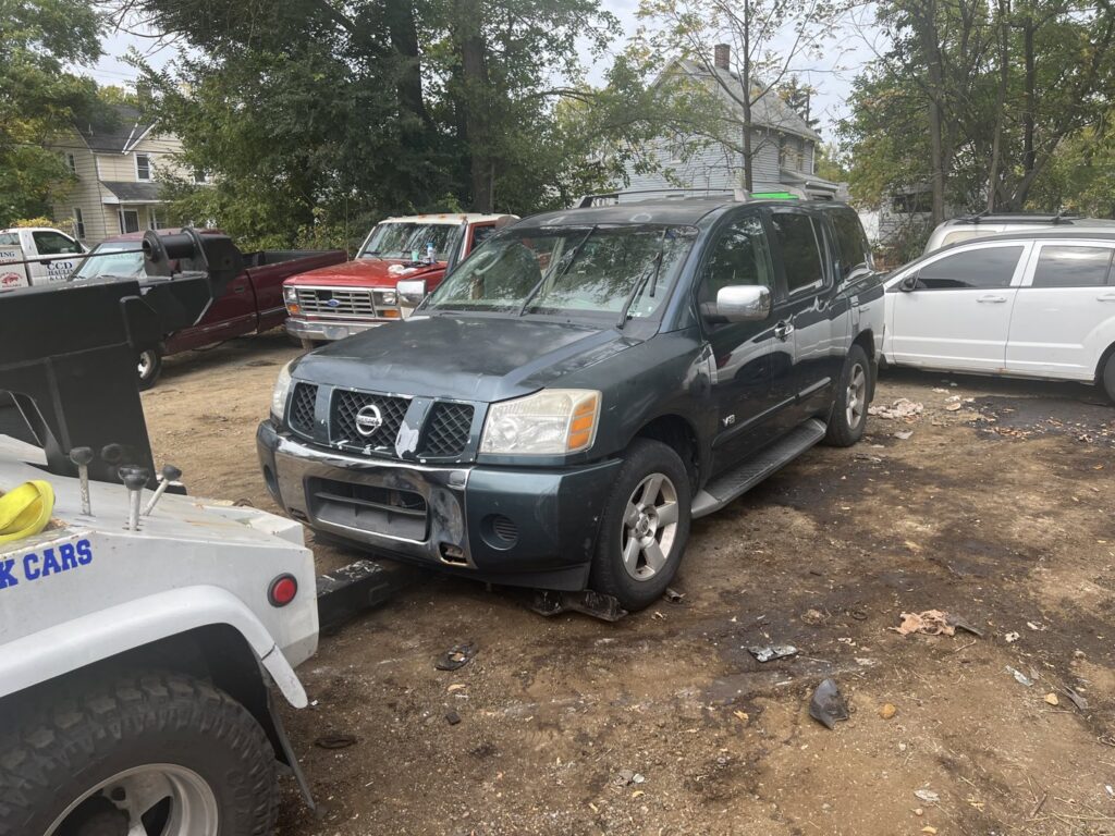 A tow truck from ALDM Management hooked to the front of a dark green Nissan Armada in a lot in Cleveland, OH.
