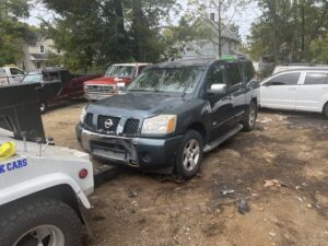A tow truck from ALDM Management hooked to the front of a dark green Nissan Armada in a lot in Cleveland, OH.