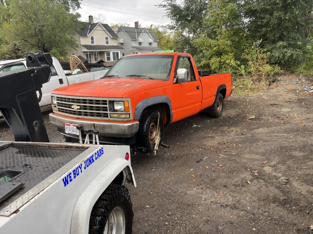 A tow truck from ALDM Management hooked to the front of an orange pickup truck in a lot in Cleveland, OH.
