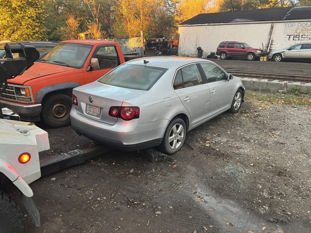A tow truck from ALDM Management hooked to the rear of a silver Volkswagen Jetta in a lot in Cleveland, OH.