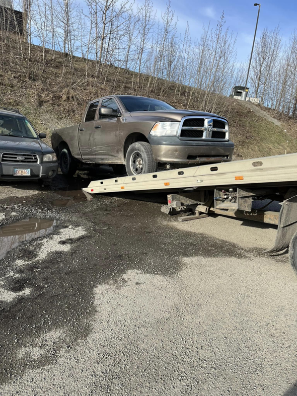A Solid Choice Towing flatbed truck loading a brown pickup truck from the roadside, providing service in Wasilla, AK.