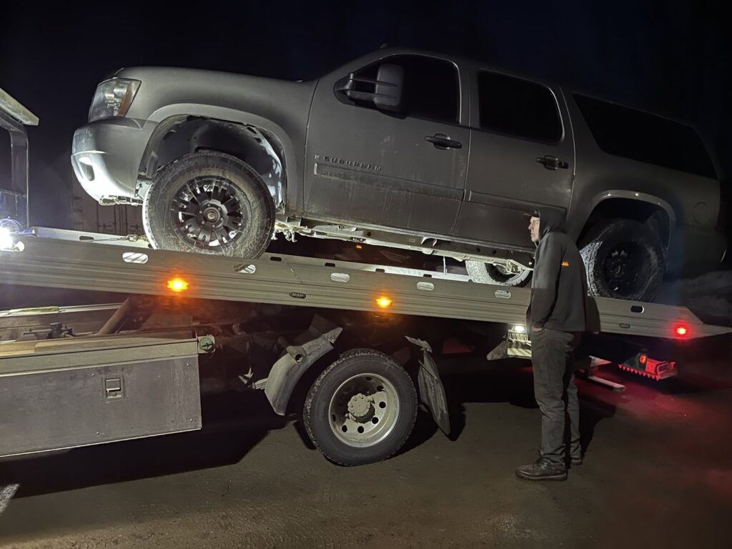 A Solid Choice Towing flatbed truck loading a large SUV during a nighttime recovery operation in Wasilla, AK.