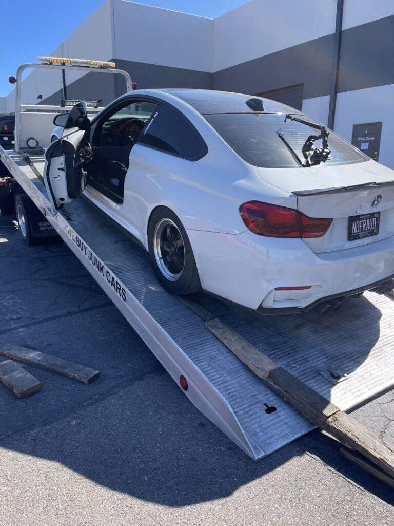 A C&B Towing flatbed truck loading a white BMW coupe using wooden ramps in Mesa, AZ.