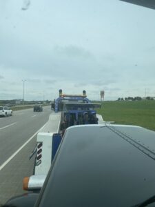 View from inside a tow truck on the highway, showing another tow truck from Jim & Ron's Service Inc. in Sioux Falls, SD.