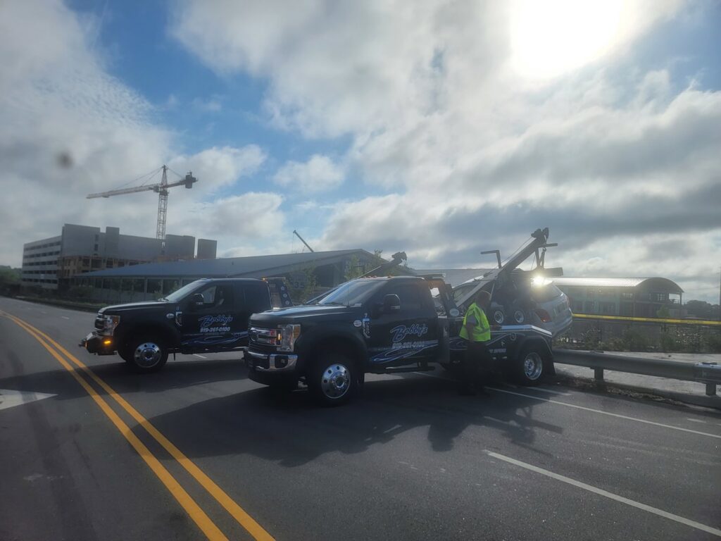 A Bobbys Towing & Recovery operator assisting a vehicle with a wrecker tow truck in Raleigh, NC.