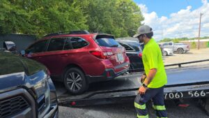 A tow truck operator from Advance Towing & Recovery loading a red SUV onto a flatbed in Columbus, GA.