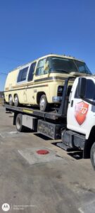 A tow truck operator loading a silver SUV onto a flatbed tow truck for AB Towing & Transport in San Antonio, TX.