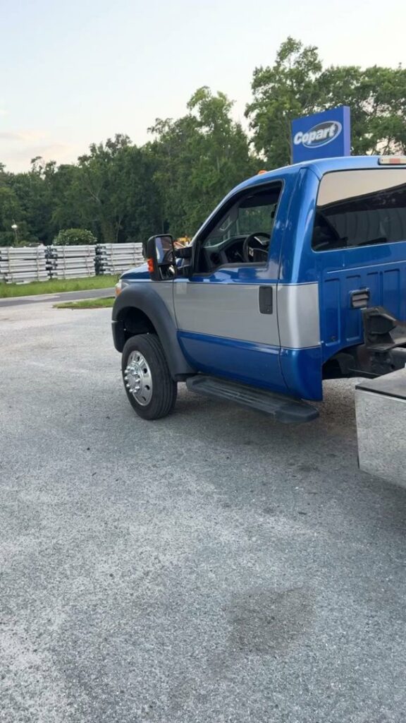 A tow truck operator securing a silver coupe for transport by Hampton Roads Towing Services in Chesapeake, VA.