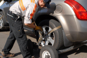 A tow truck operator securing a car wheel with straps for Emergency Towing San Francisco in San Francisco, CA.