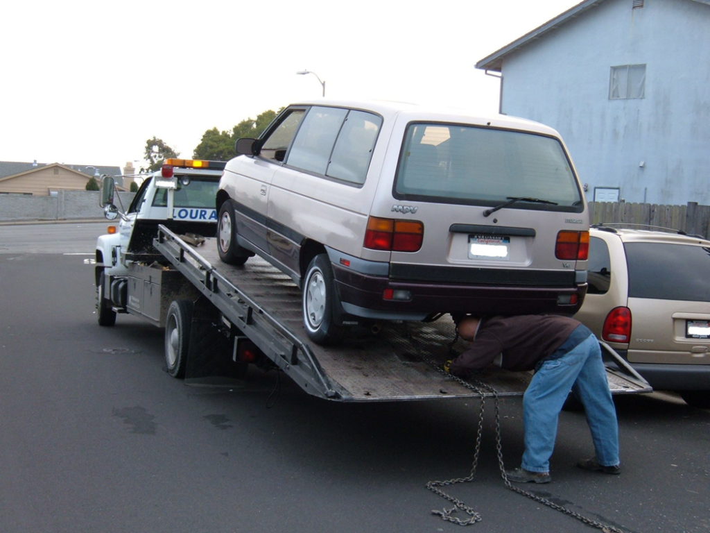 A tow truck operator securing a minivan onto a flatbed tow truck for A1 Towing Las Vegas Henderson, NV.