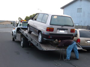 A tow truck operator securing a minivan onto a flatbed tow truck for A1 Towing Las Vegas Henderson, NV.