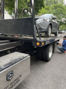 An Elite Towing of Minnesota operator securing a grey SUV onto a flatbed tow truck in St Paul, MN.