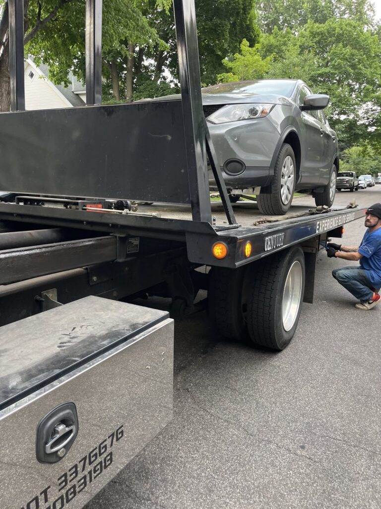 An Elite Towing of Minnesota operator securing a grey SUV onto a flatbed tow truck in St Paul, MN.