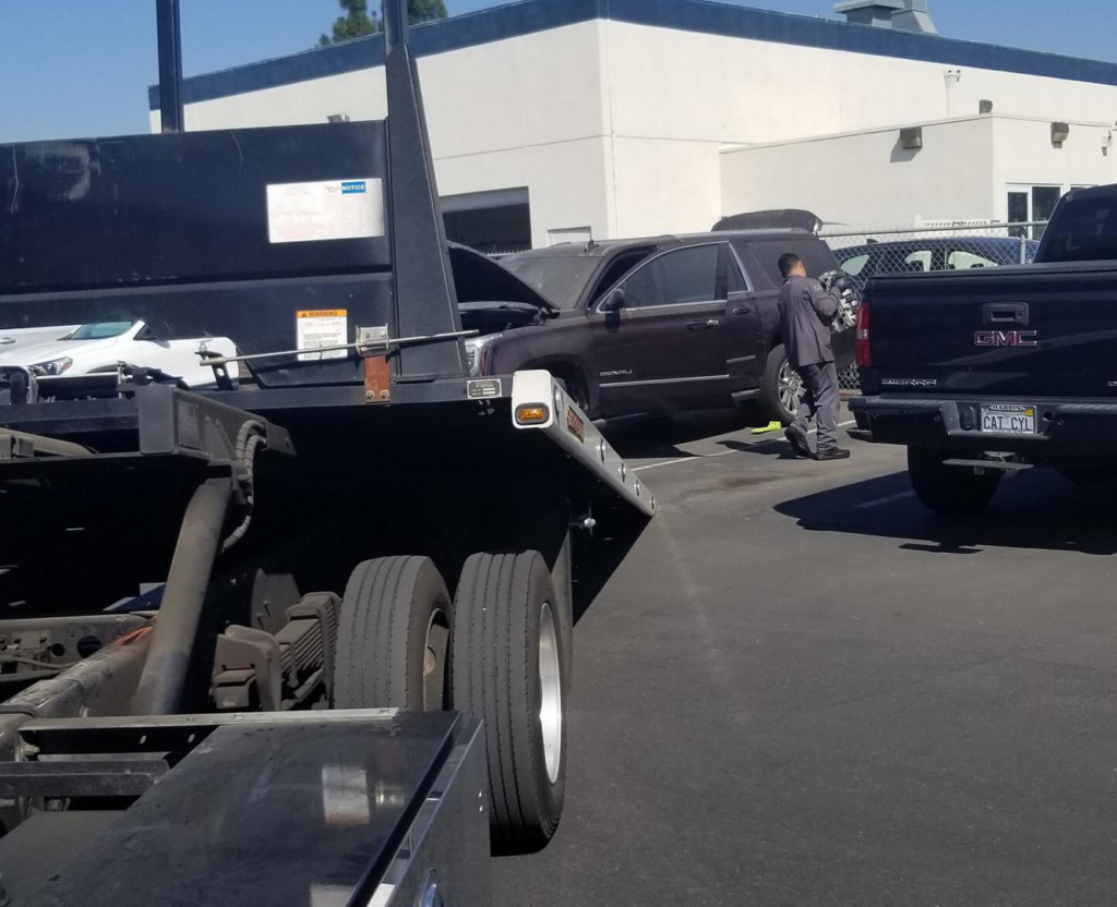 A tow truck from Leos Towing Service preparing to load a disabled SUV with its hood open in Anaheim, CA.