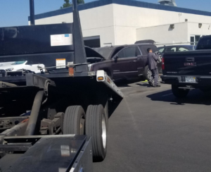 A tow truck from Leos Towing Service preparing to load a disabled SUV with its hood open in Anaheim, CA.