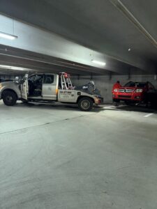 An A-Tow Atlanta / Alpharetta tow truck preparing to hook up a red SUV for towing in a parking garage in Atlanta, GA.