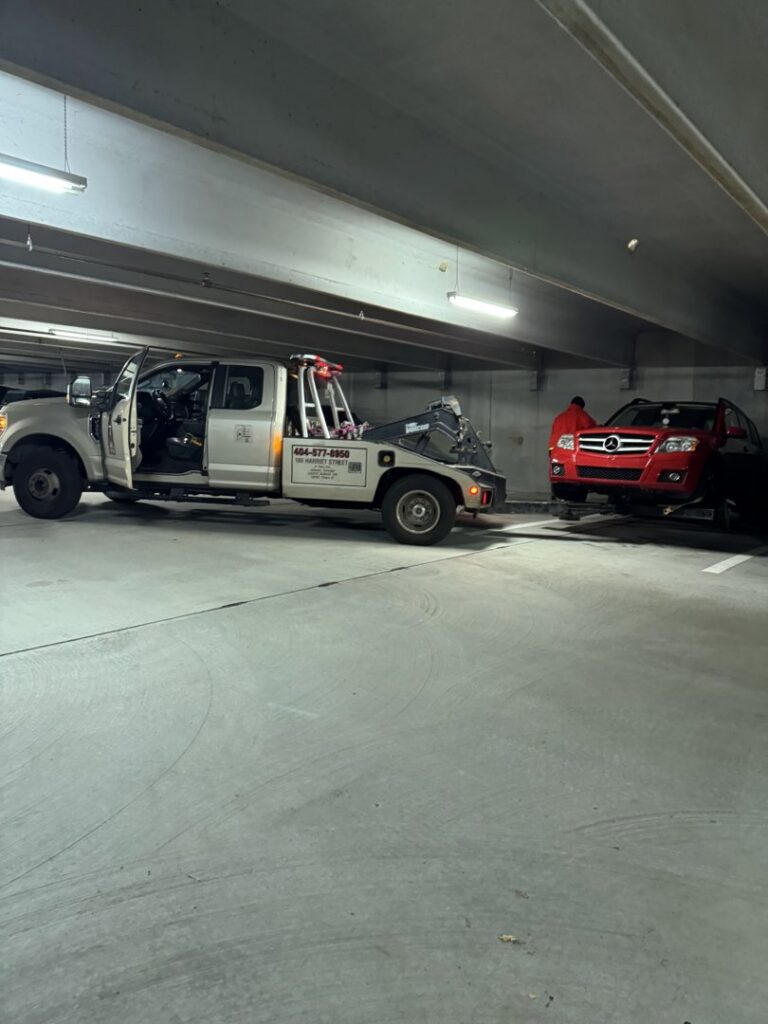 An A-Tow Atlanta / Alpharetta tow truck preparing to hook up a red SUV for towing in a parking garage in Atlanta, GA.