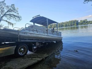 A Pro-Tech Wrecker Service tow truck recovering a pontoon boat from the water in Decatur, AL.
