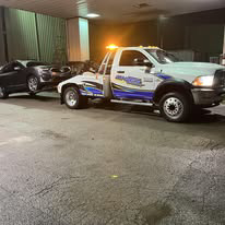 A White's Wrecker Service tow truck towing a black car at night in Memphis, TN.