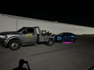 A Hound Dog's Towing & Recovery truck towing a blue sedan at night in Columbus, OH.
