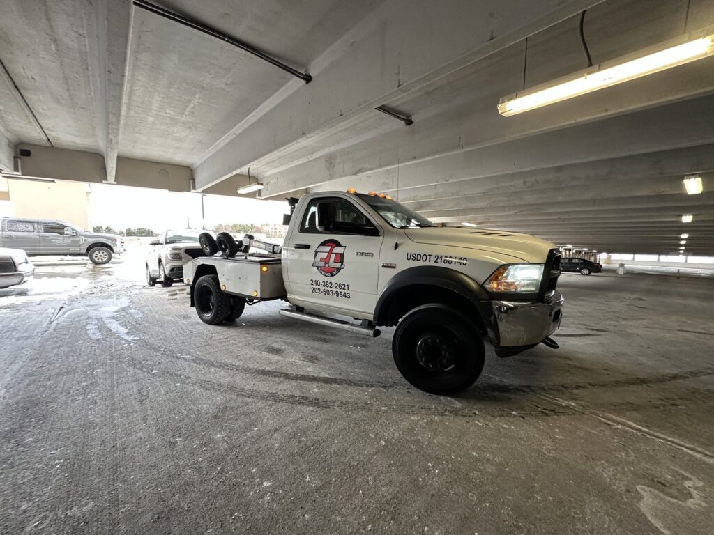 An E.C. Towing, Inc. tow truck towing a car inside a parking garage in Gaithersburg, MD.