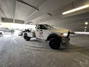 An E.C. Towing, Inc. tow truck towing a car inside a parking garage in Gaithersburg, MD.