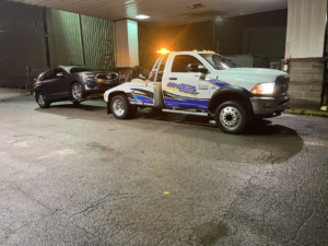 A White's Wrecker Service tow truck towing a dark SUV at night in Memphis, TN.