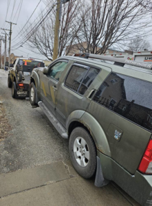 A tow truck from Soto Towing Inc. towing a green SUV down a street in Chicago, IL.