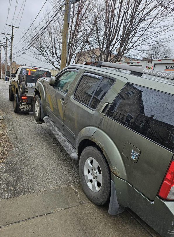 A tow truck from Soto Towing Inc. towing a green SUV down a street in Chicago, IL.