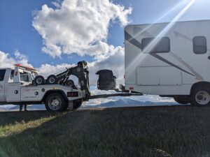 A Carnahan's Towing & Repair Inc. tow truck providing roadside assistance for an RV in Great Falls, MT.