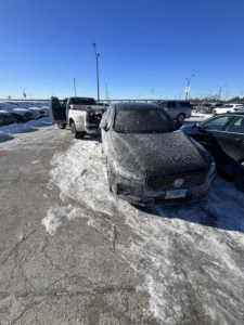 A Trevi Towing llc truck towing a dark sedan in a snowy parking lot in Chicago, IL.