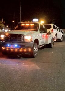 An E.C. Towing, Inc. tow truck towing a white SUV at night in Gaithersburg, MD.