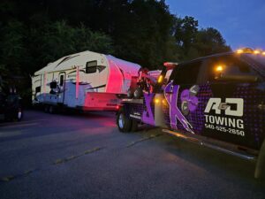 An A and D Towing truck is seen towing a large white travel trailer or RV at dusk in Little Ferry, NJ.