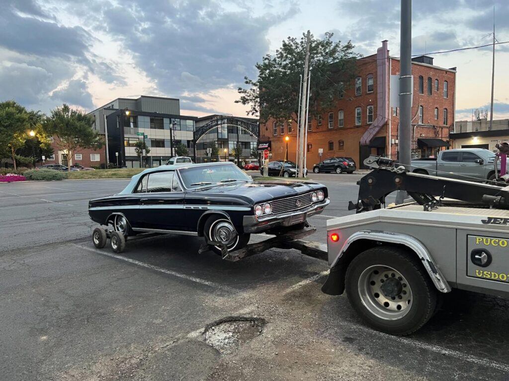 A Hound Dog's Towing & Recovery truck towing a vintage car with dollies in Columbus, OH.