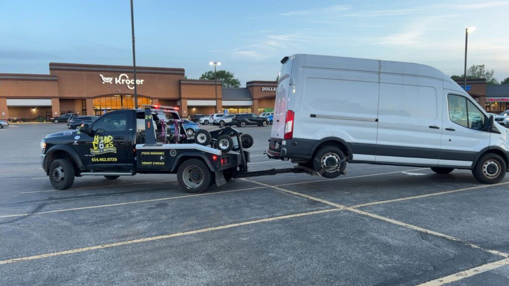 A Hound Dog's Towing & Recovery tow truck towing a white van with a wheel lift in Columbus, OH.