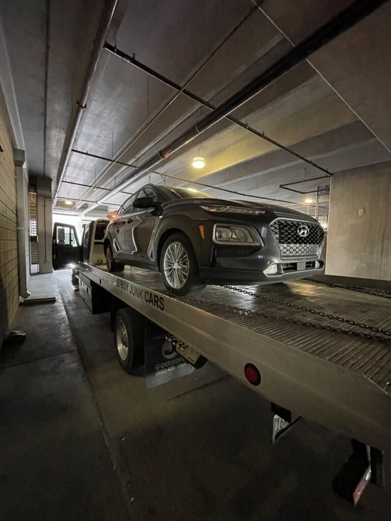 A C&B Towing flatbed truck transporting a dark grey SUV in a parking garage in Mesa, AZ.